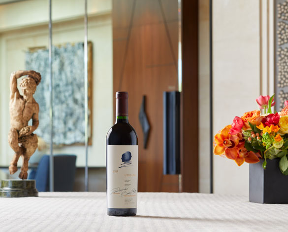 A bottle of Opus One 2014 with pink and orange florals on the right side, and a dancing figurine on the left.
