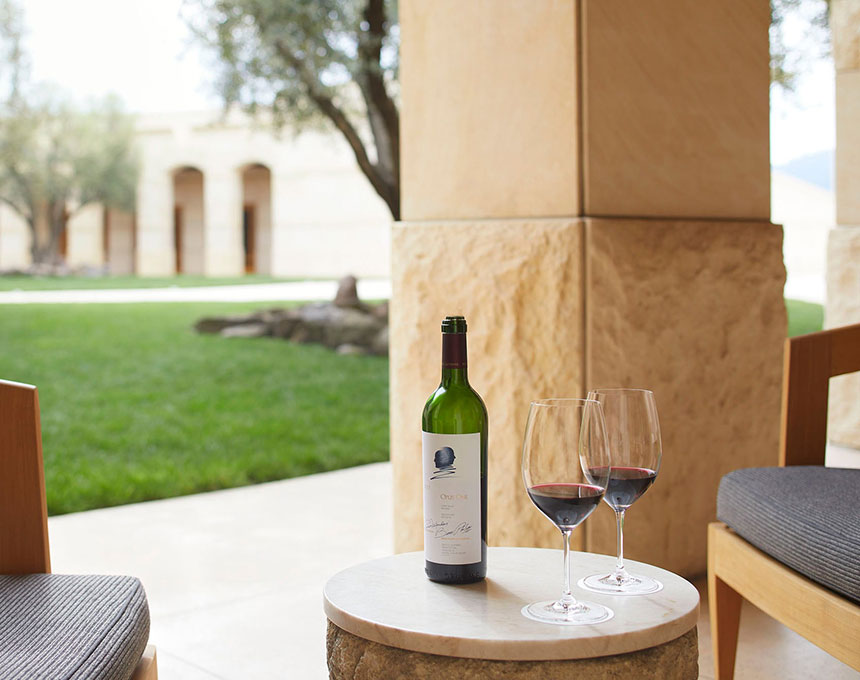 A bottle of Opus One next to two wine glasses in the courtyard tasting area
